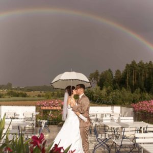 hochzeitsfotografin zeigt hochzeitsbilder für reportage mit regenbogen und schirm in bamberg