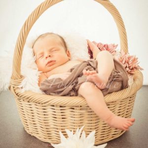 babyfotos im korb mit blumen bei neugeborenenshooting zuhause von fotografin